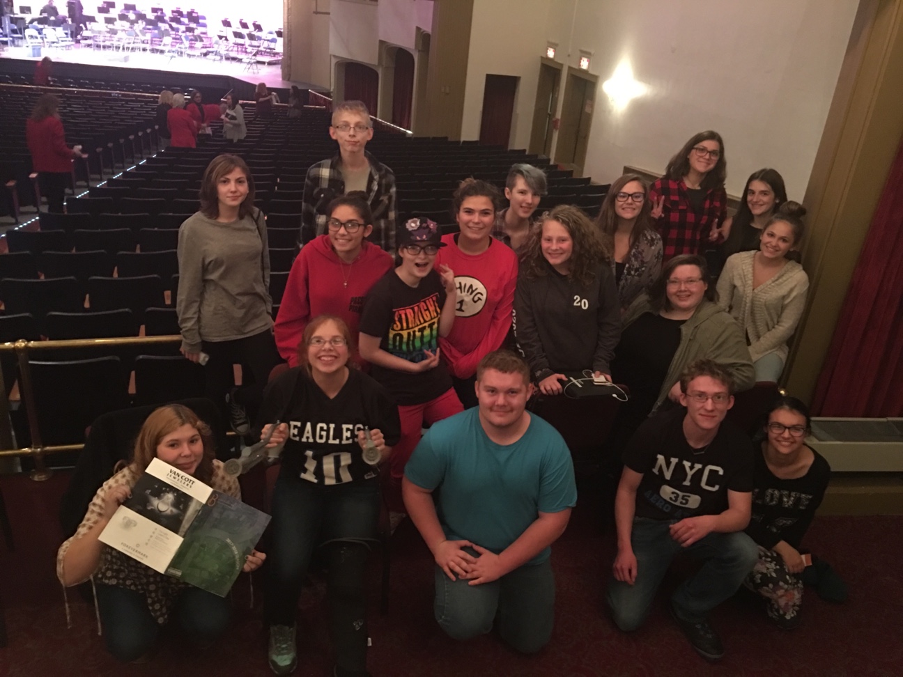 18 students posing for a picture in a theater.