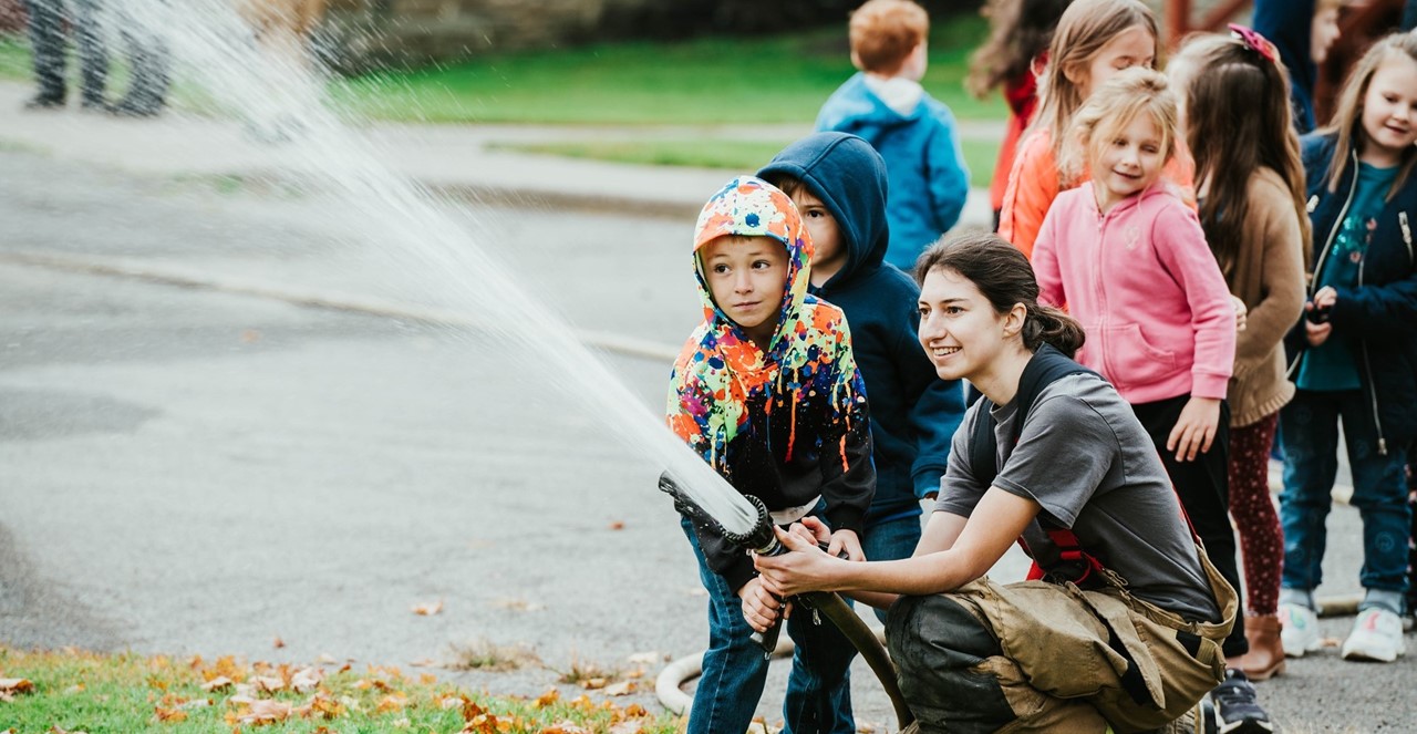 Firefighter helps student hold hose