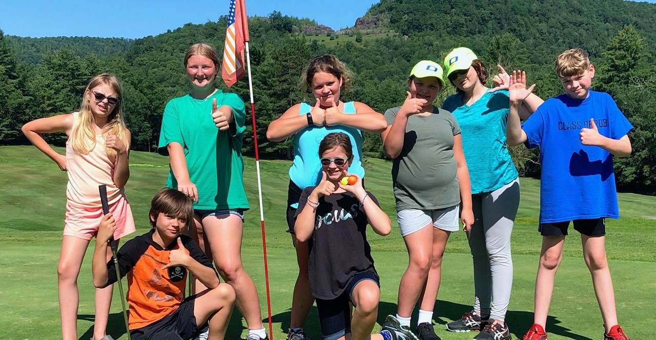 students on golf course give thumbs up