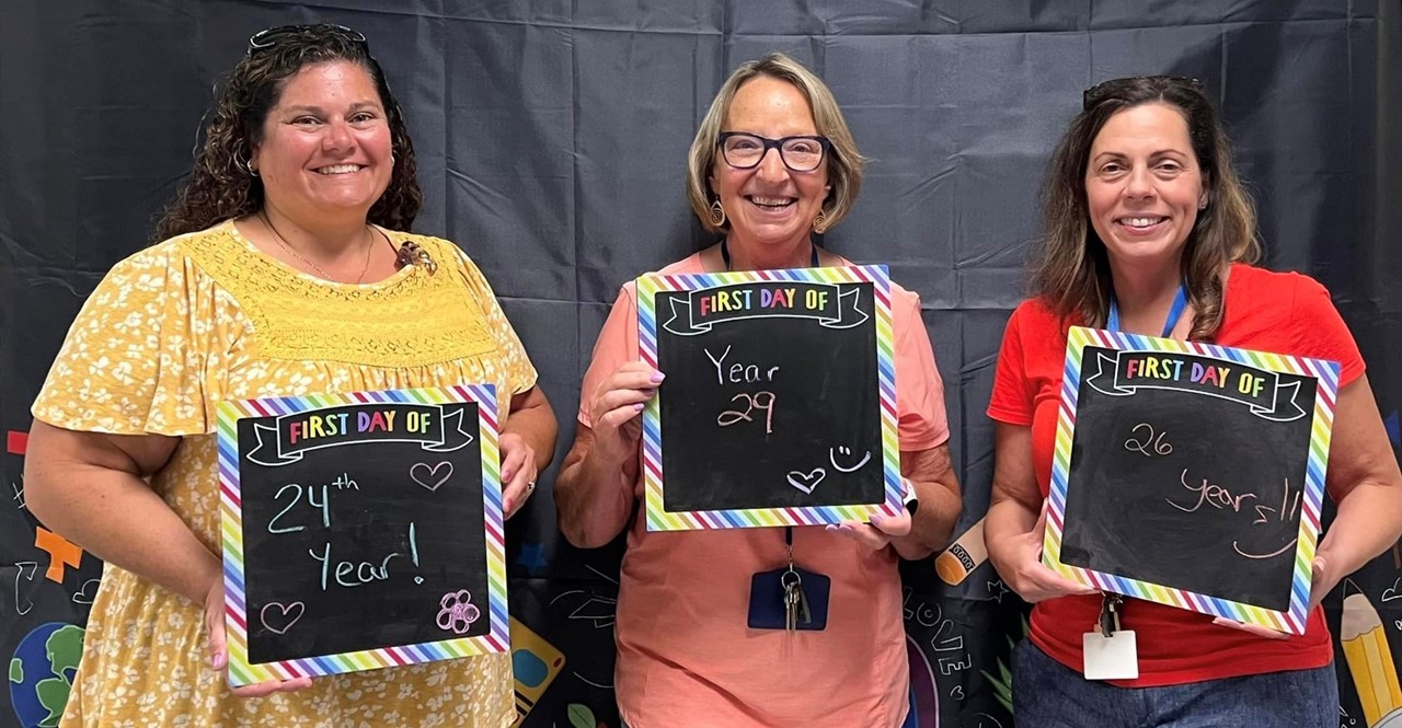 Teachers hold signs with years of service