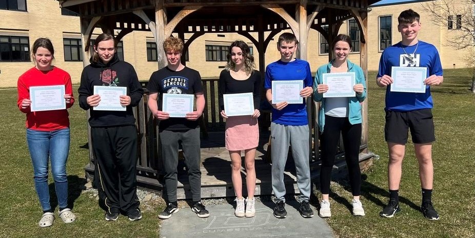 Group of students hold certificates outside gazebo