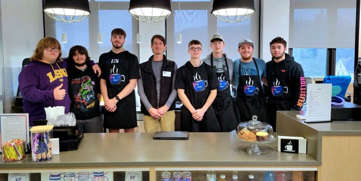 Group of students pose with visitor to high school cafe
